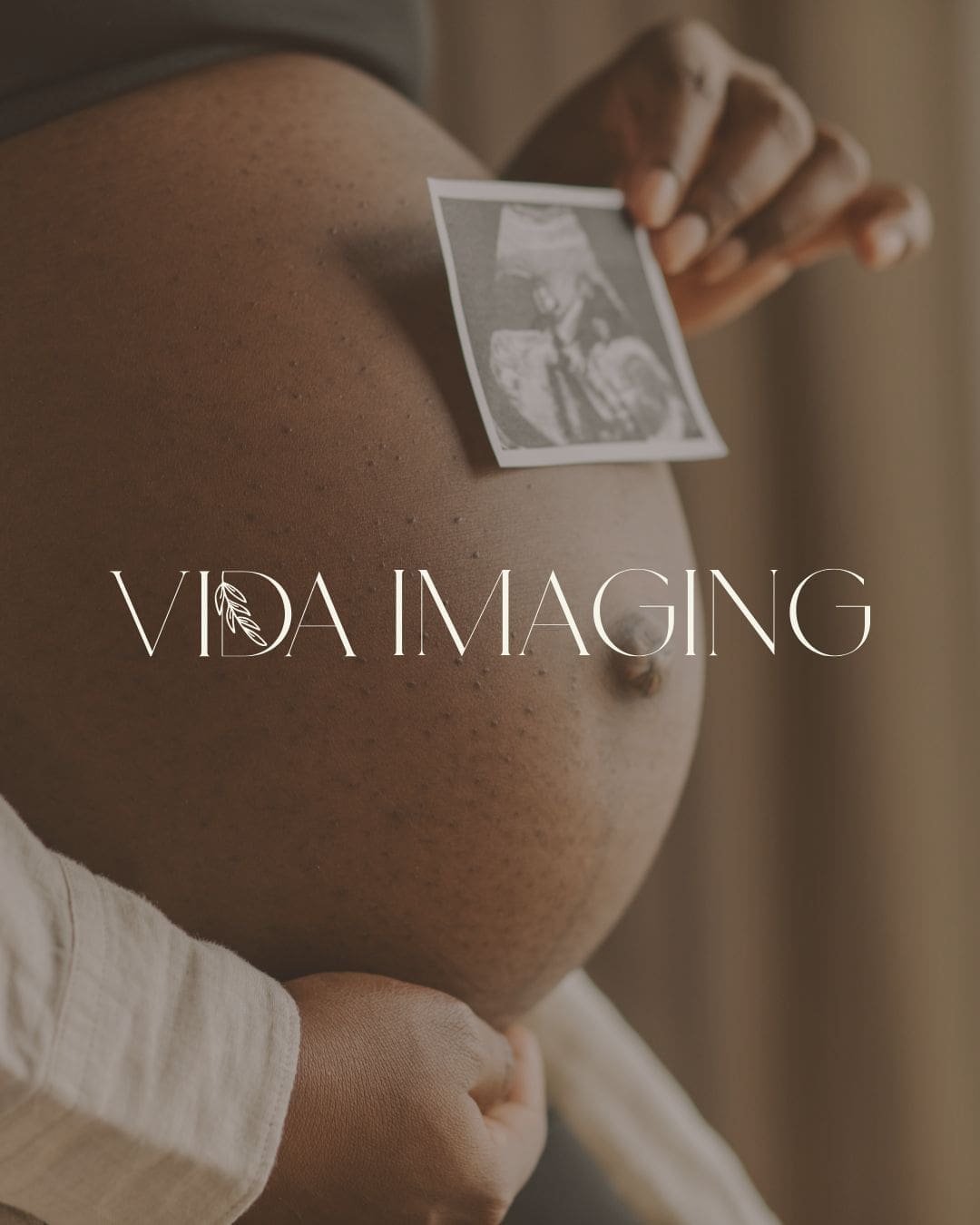 Pregnant person holding an ultrasound photo against their baby bump, representing prenatal care, pregnancy, and maternal wellness.
